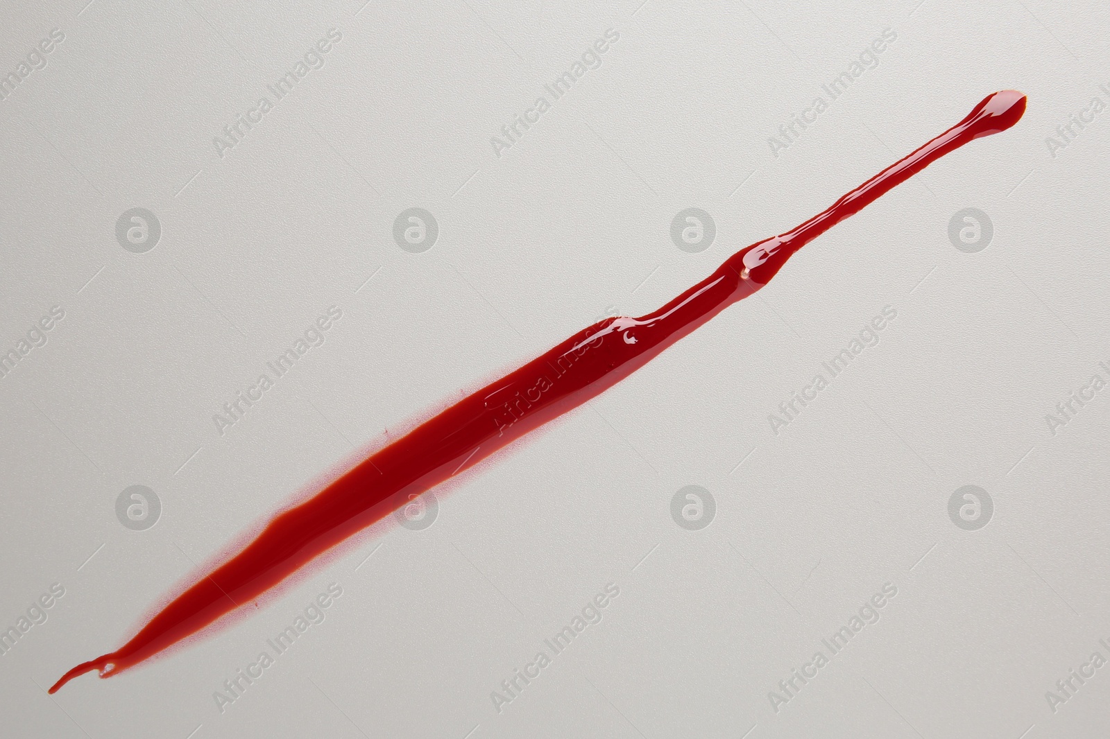 Photo of Splash of red blood on light background