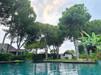 Photo of Swimming pool near beautiful trees. Luxury resort