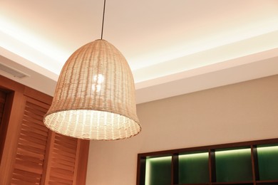 Stylish pendant lamp on ceiling indoors, low angle view