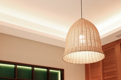 Photo of Stylish pendant lamp on ceiling indoors, low angle view