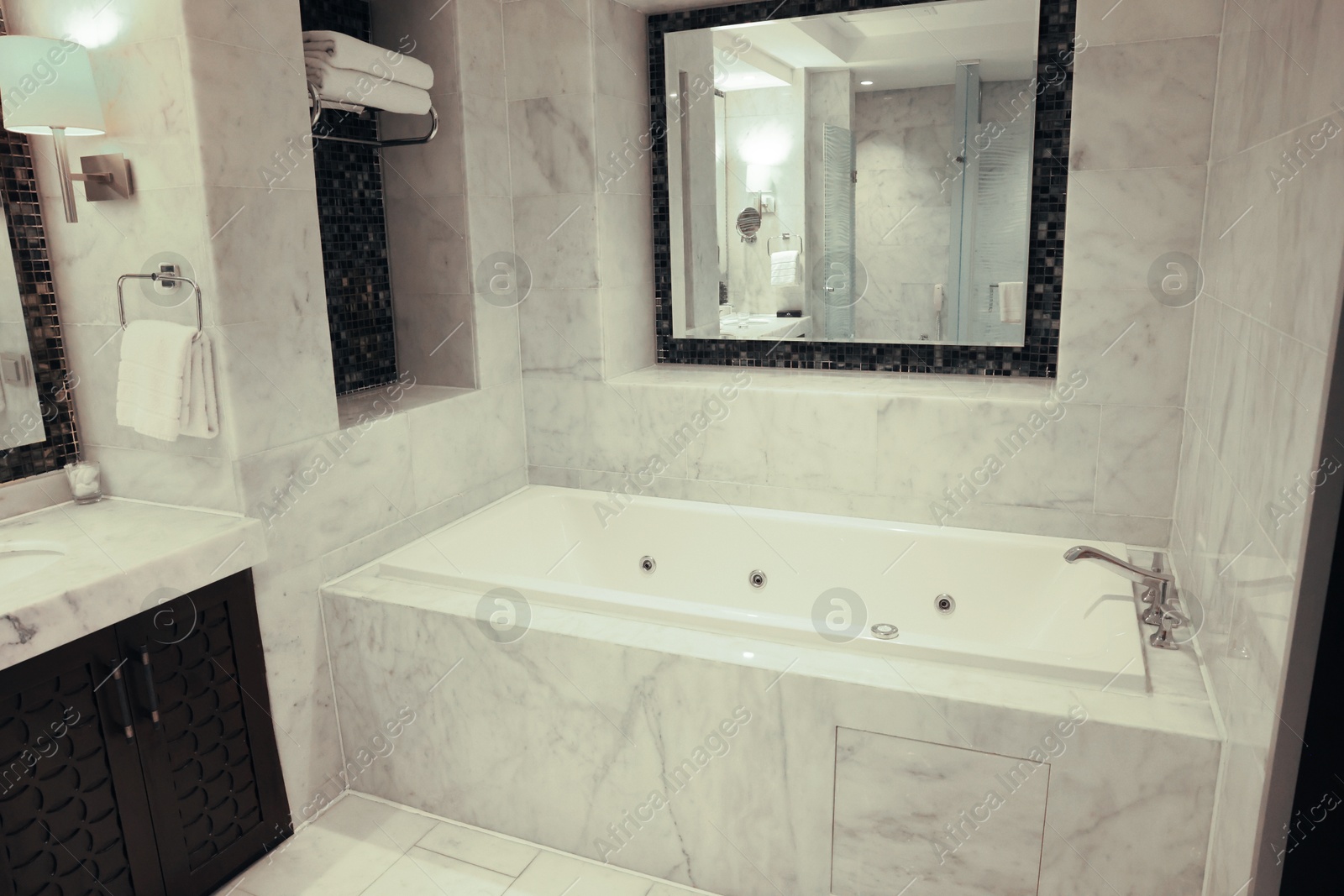 Photo of Stylish bathroom with marble bathtub and mirror in luxury hotel