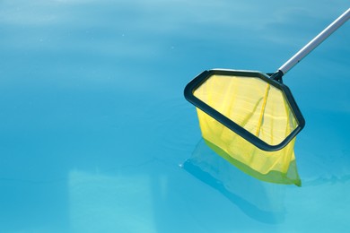 Photo of Cleaning swimming pool with skimmer net on sunny day