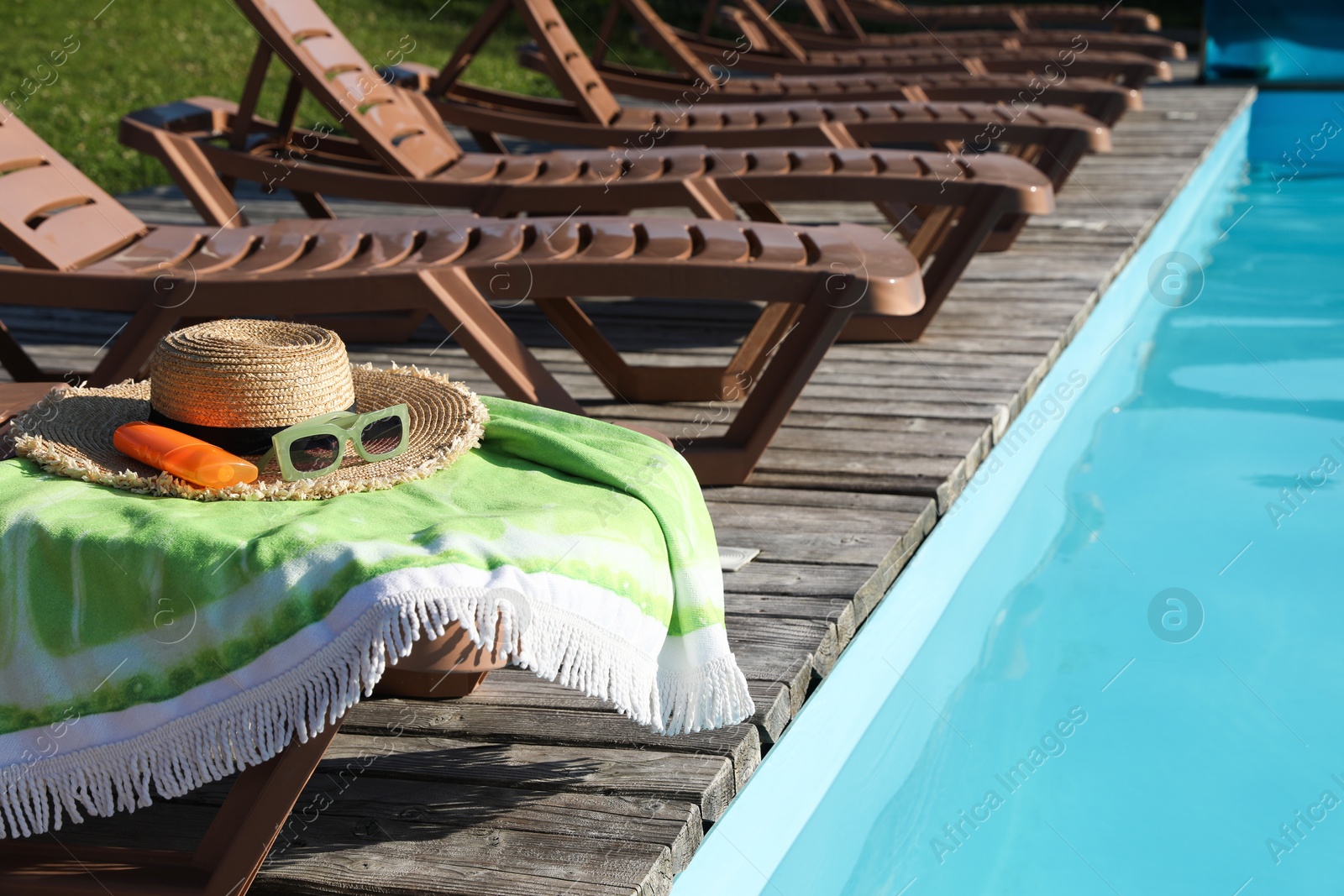 Photo of Beach accessories and sun loungers on wooden deck near outdoor swimming pool