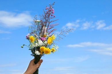 Photo of Woman holding bouquet of wild flowers outdoors, closeup