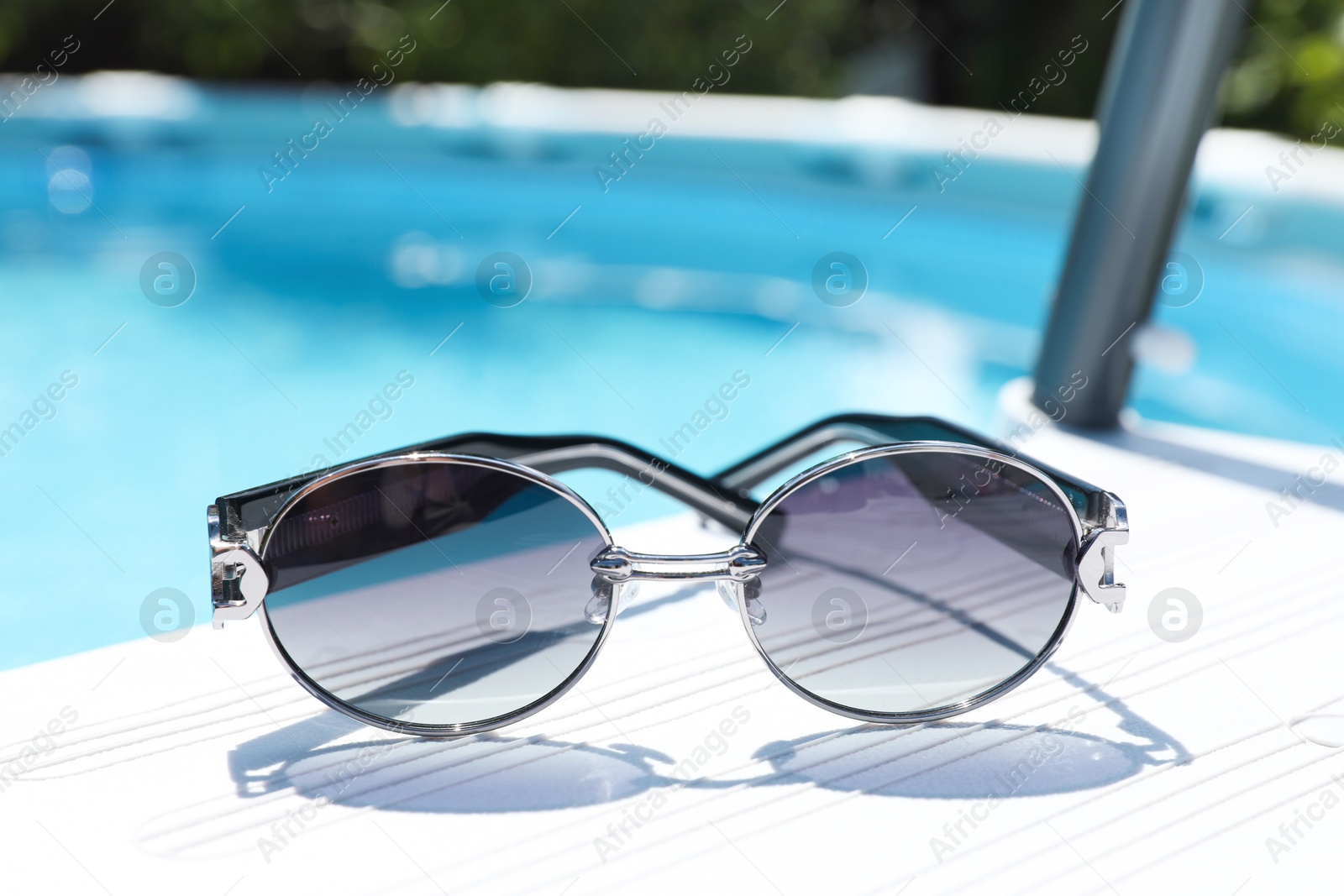 Photo of One pair of sunglasses near swimming pool outdoors