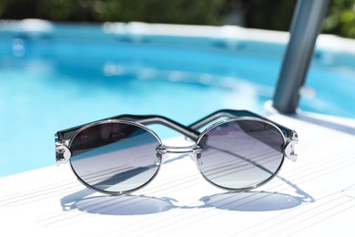 Photo of One pair of sunglasses near swimming pool outdoors