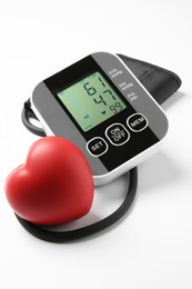 Photo of Blood pressure measuring device and red heart figure on light grey background