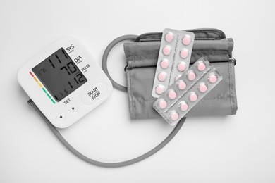 Blood pressure measuring device and pill blisters on light grey background, flat lay