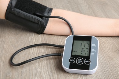 Woman measuring blood pressure at wooden table, closeup