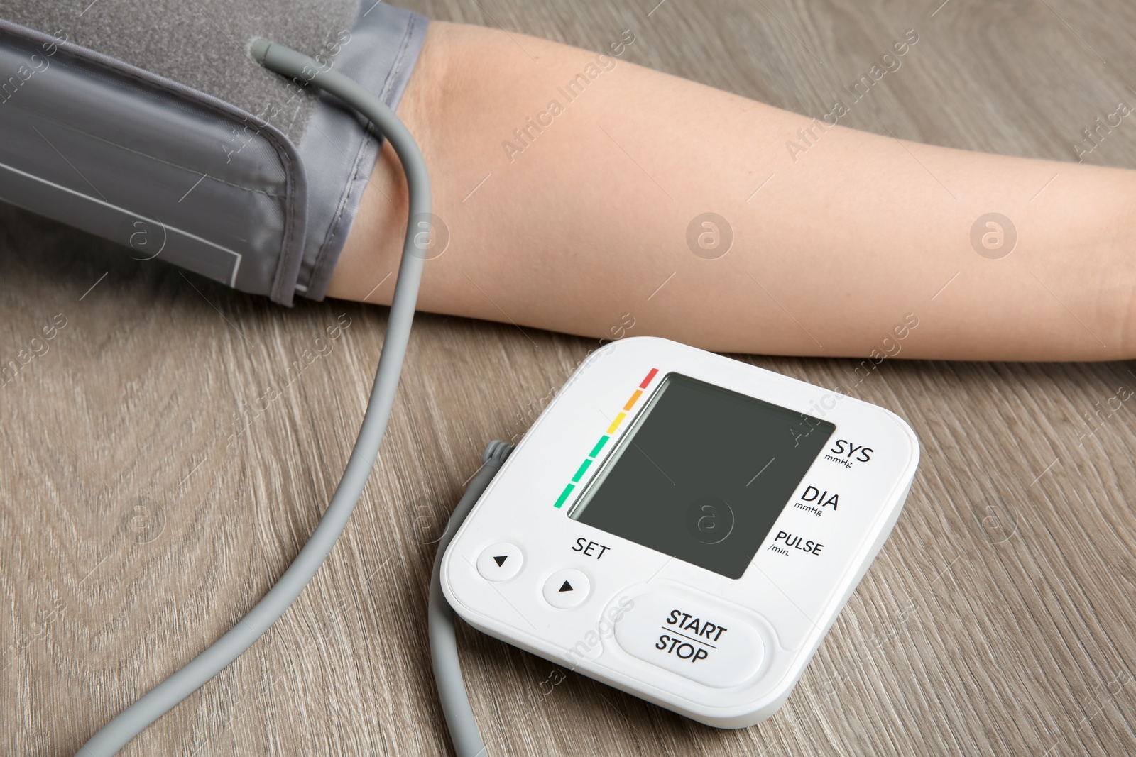 Photo of Woman measuring blood pressure at wooden table, closeup