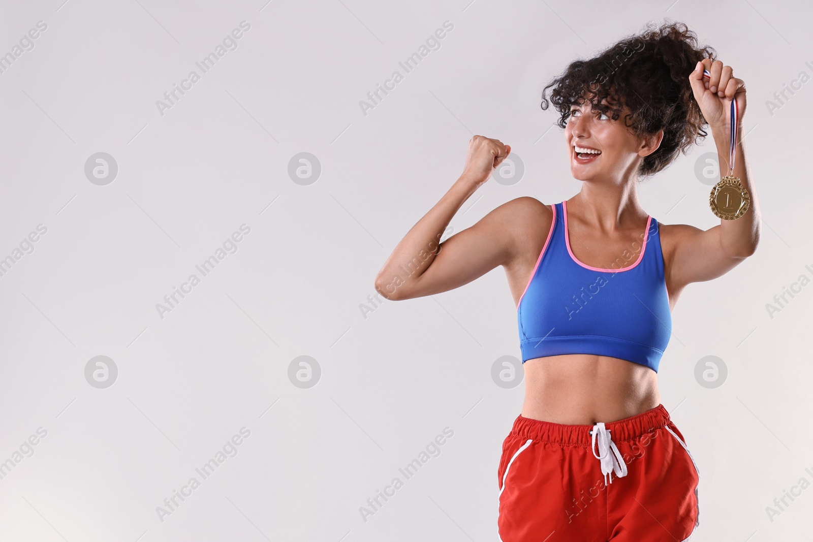 Photo of Happy winner with golden medal on light grey background. Space for text