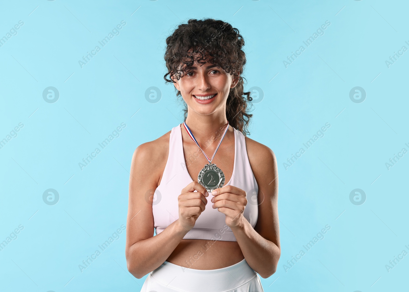 Photo of Happy winner with silver medal on light blue background