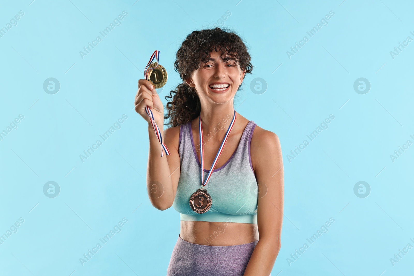 Photo of Happy winner with different medals on light blue background