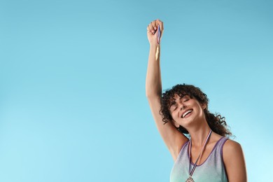 Photo of Happy winner showing golden medal on light blue background. Space for text