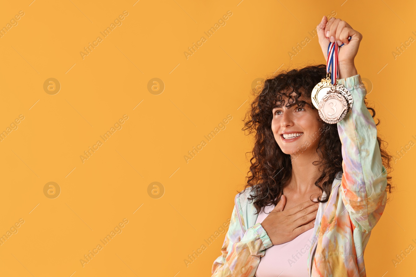 Photo of Happy winner showing different medals on yellow background. Space for text