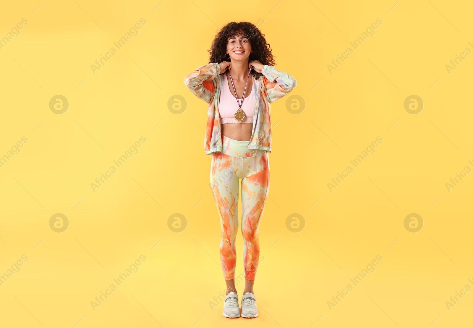 Photo of Happy winner with golden medal on yellow background