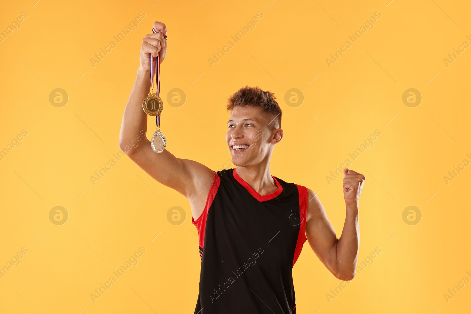 Photo of Happy winner with different medals on yellow background