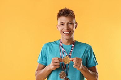 Photo of Happy winner with different medals on yellow background