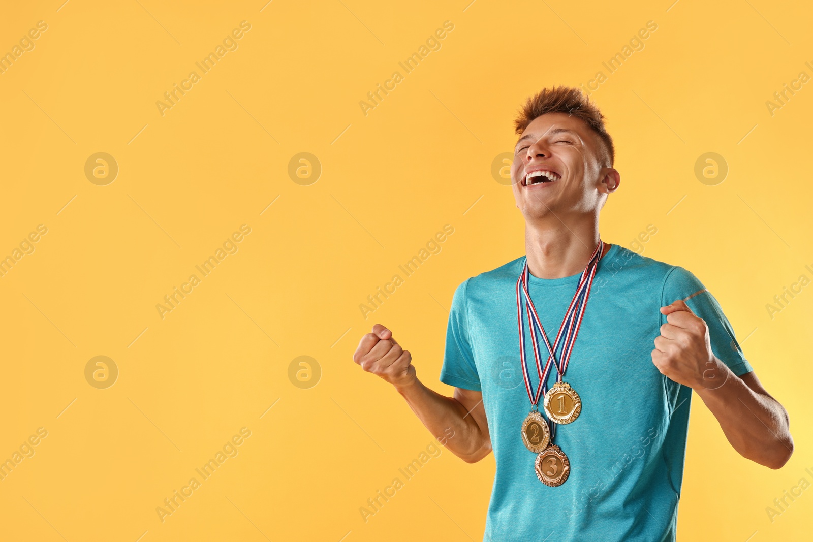 Photo of Happy winner with different medals on yellow background. Space for text