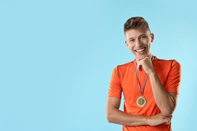 Photo of Happy winner with golden medal on light blue background. Space for text