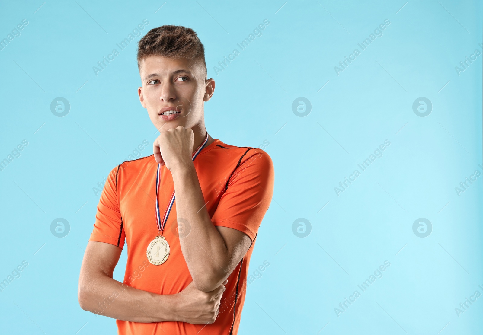 Photo of Handsome winner with medal on light blue background. Space for text