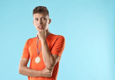 Photo of Handsome winner with medal on light blue background. Space for text