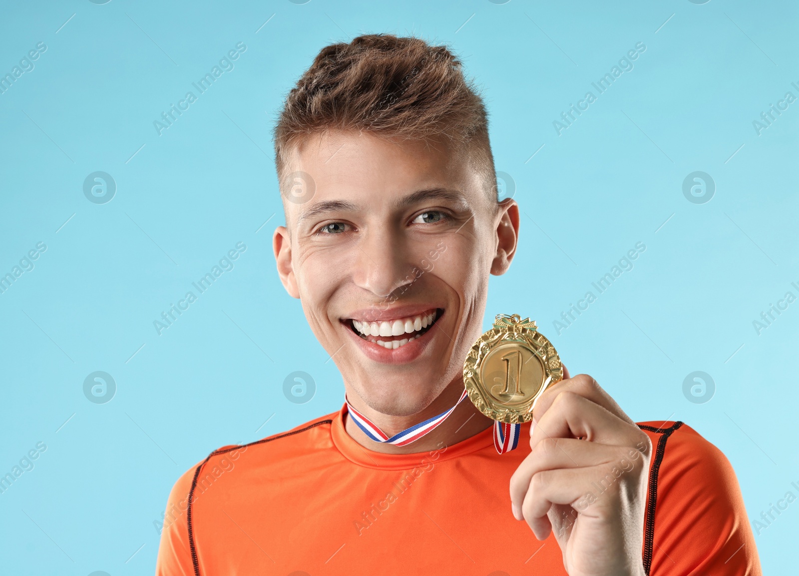 Photo of Happy winner with golden medal on light blue background