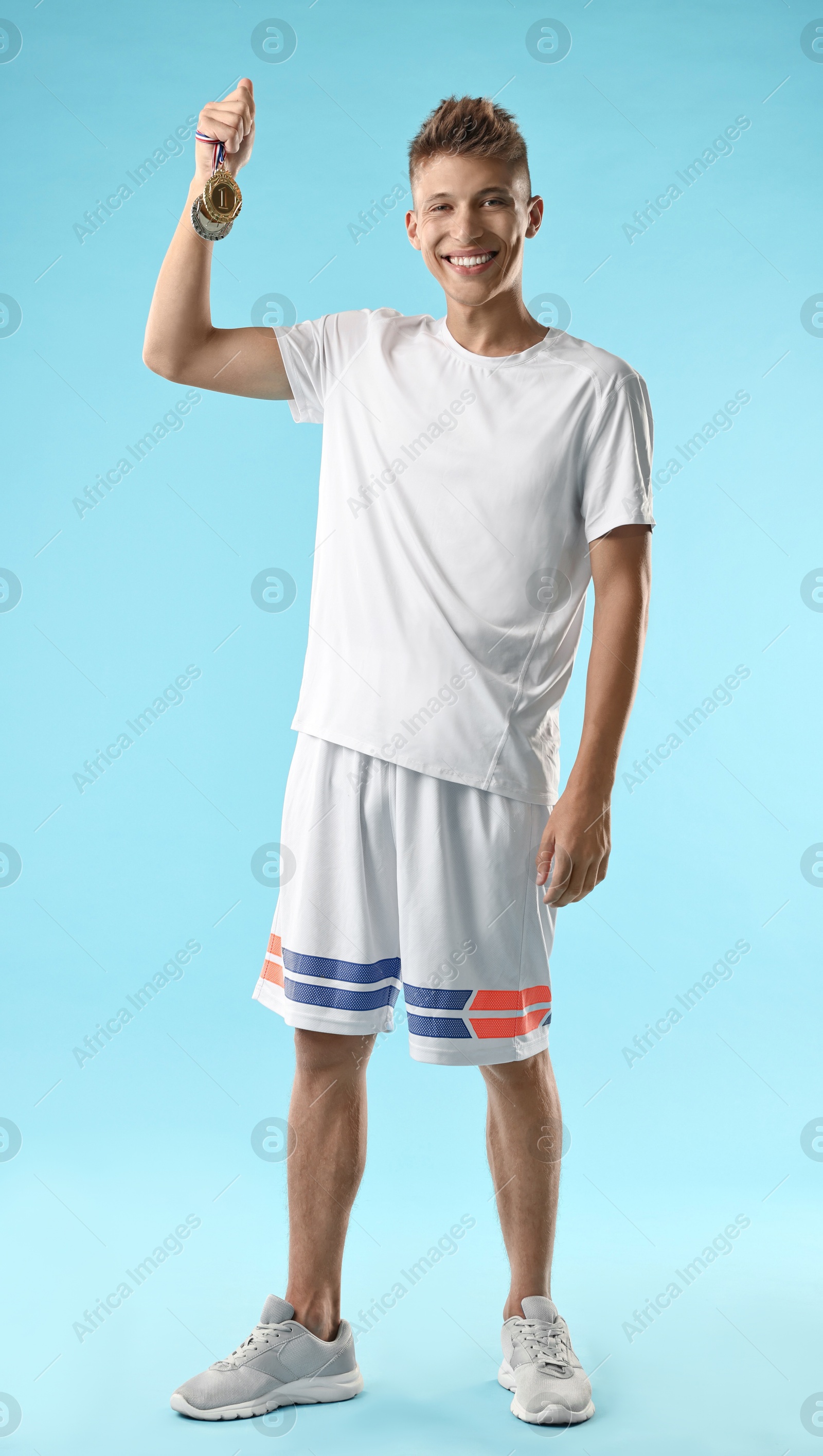 Photo of Happy winner with different medals on light blue background