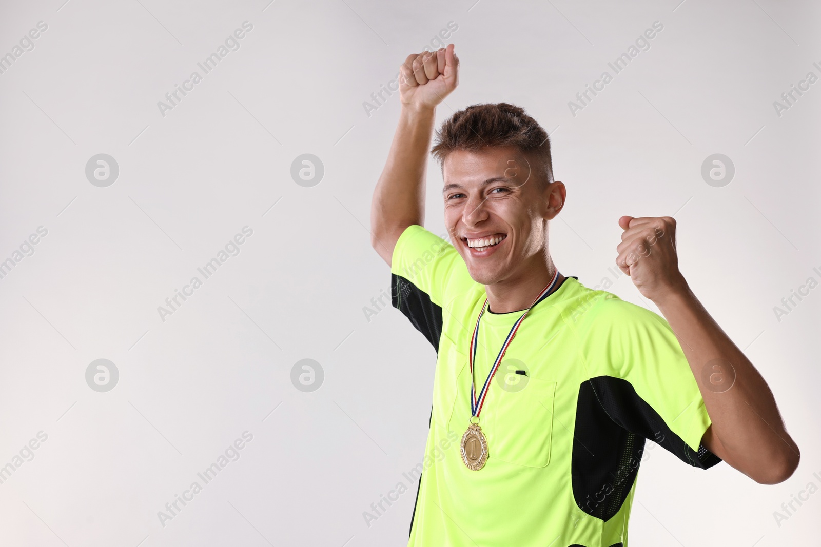 Photo of Happy winner with golden medal on light grey background. Space for text