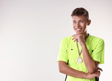 Photo of Happy winner with golden medal on light grey background. Space for text