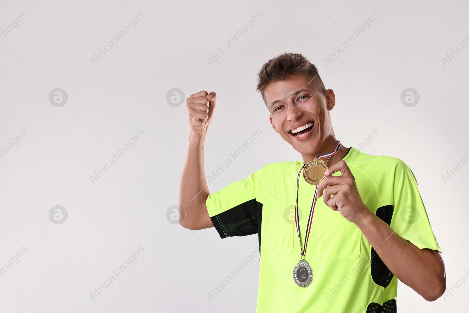 Photo of Happy winner with different medals on light grey background. Space for text