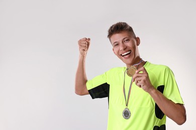 Happy winner with different medals on light grey background. Space for text