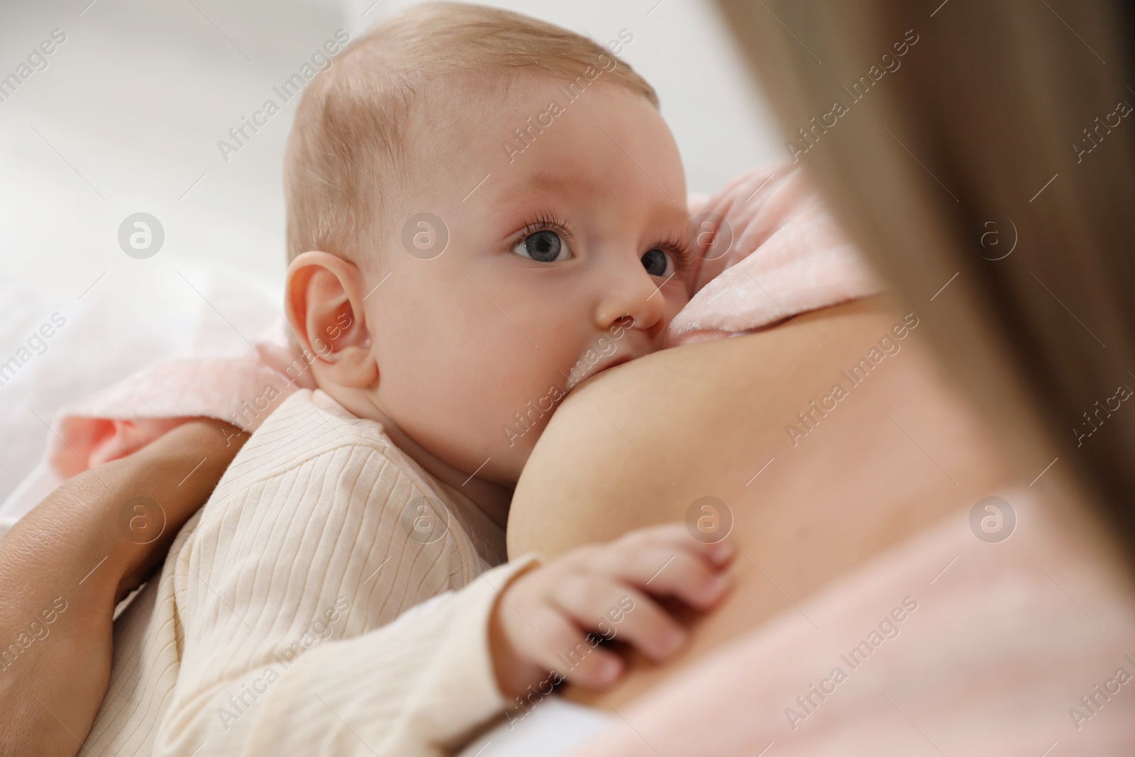 Photo of Mother breastfeeding her little baby indoors, closeup