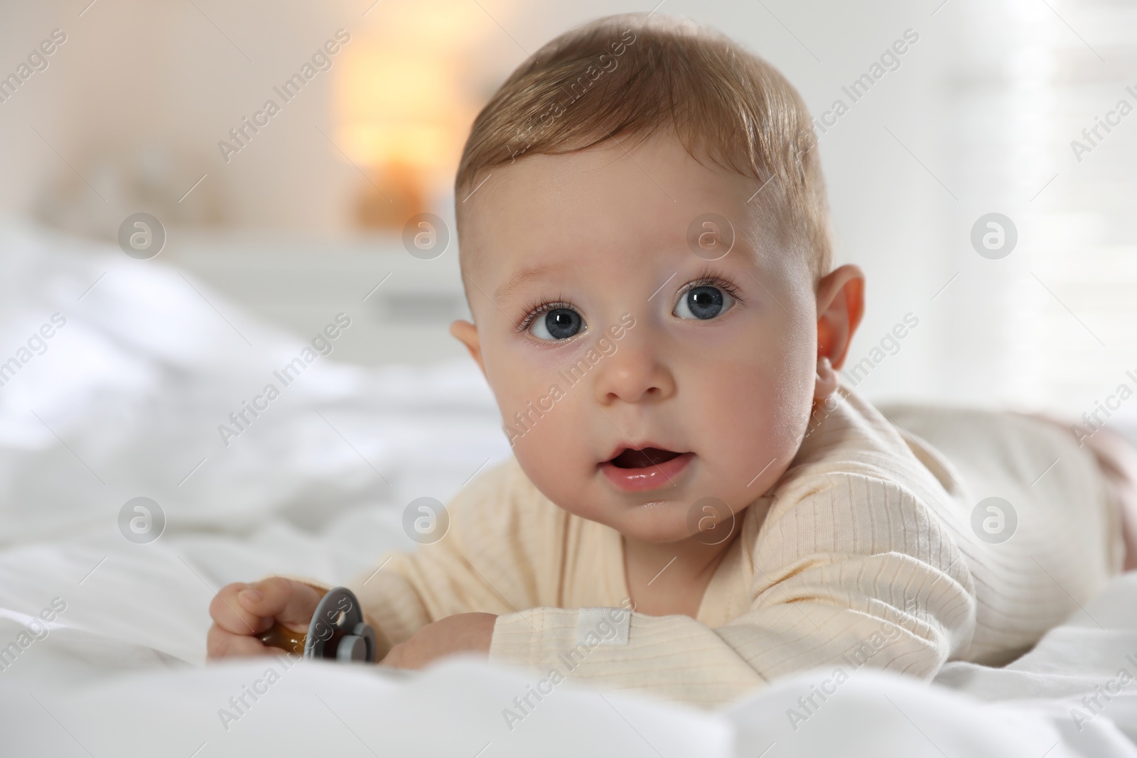 Photo of Cute little baby with pacifier on bed indoors