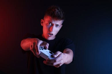 Photo of Young man playing video games with controller on black background