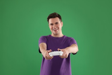 Photo of Happy young man playing video games with controller on green background