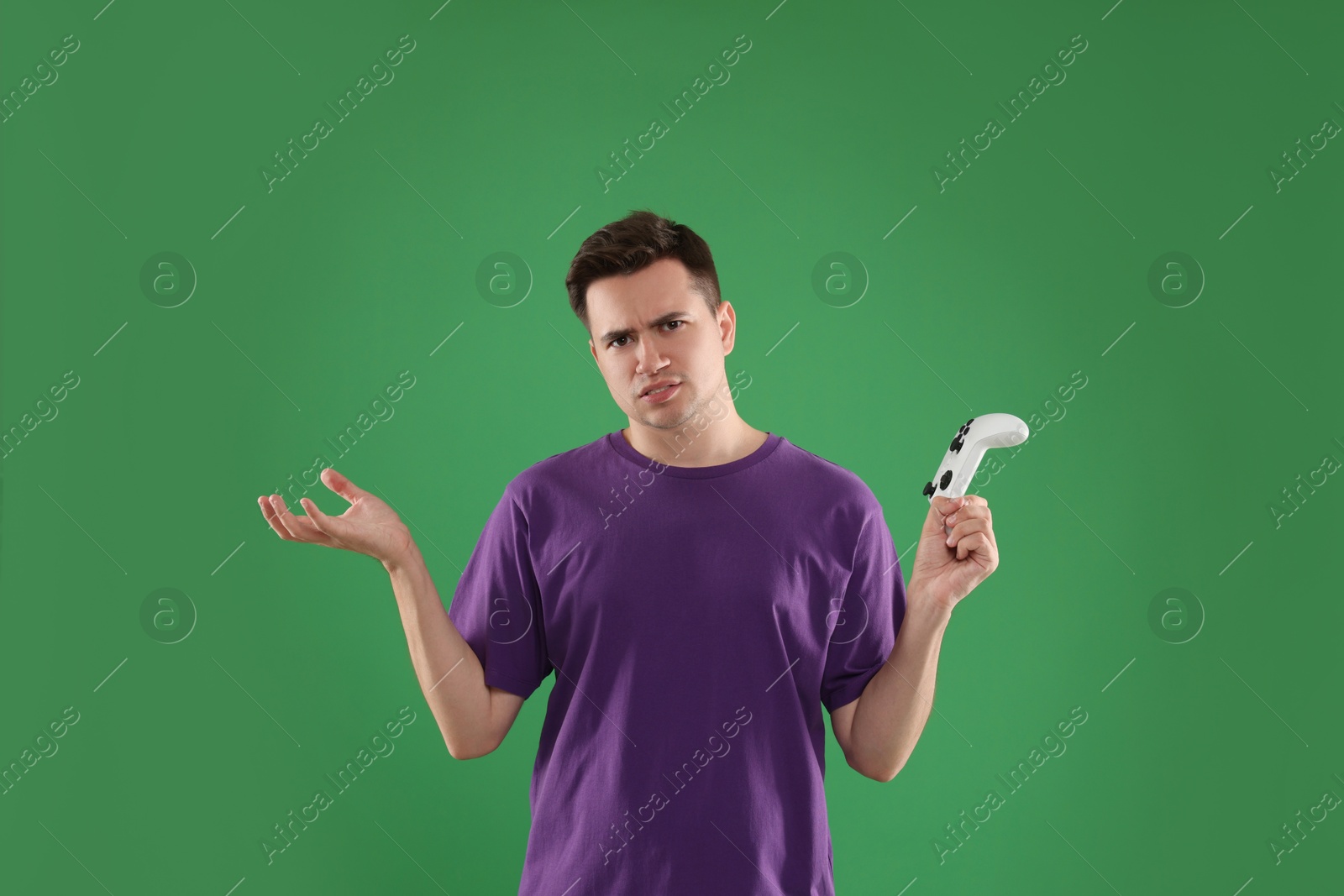 Photo of Young man playing video games with controller on green background