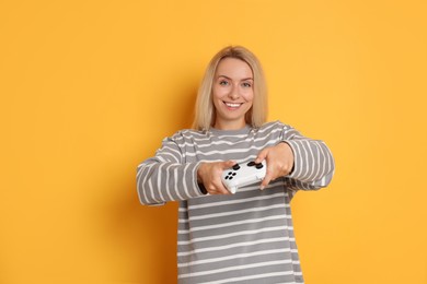 Photo of Happy woman playing video games with controller on orange background