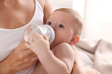 Mother feeding her cute child indoors, closeup