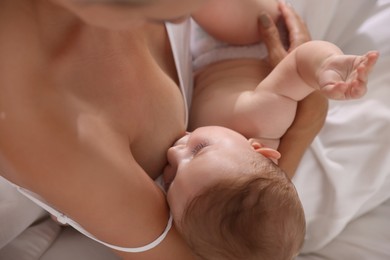 Photo of Mother breastfeeding her little baby indoors, above view