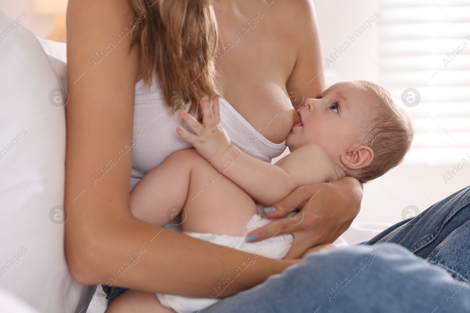 Photo of Mother breastfeeding her little baby indoors, closeup