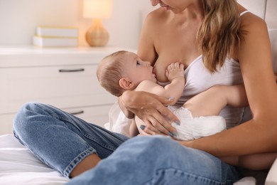 Photo of Mother breastfeeding her little baby indoors, closeup