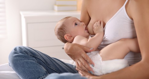 Mother breastfeeding her little baby indoors, closeup