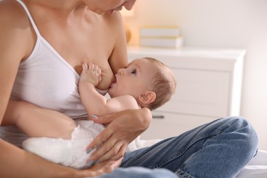 Mother breastfeeding her little baby indoors, closeup