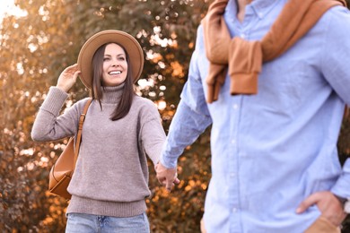 Beautiful couple walking together in park on autumn day, selective focus