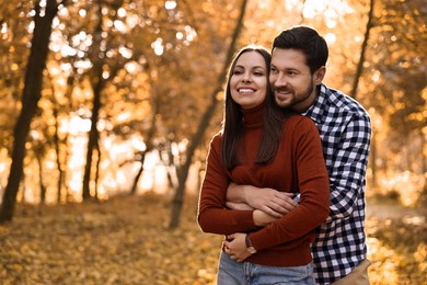 Beautiful couple spending time in park on autumn day, space for text