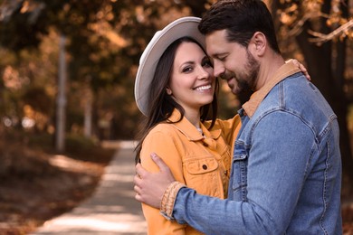 Photo of Beautiful couple hugging in park on autumn day, space for text