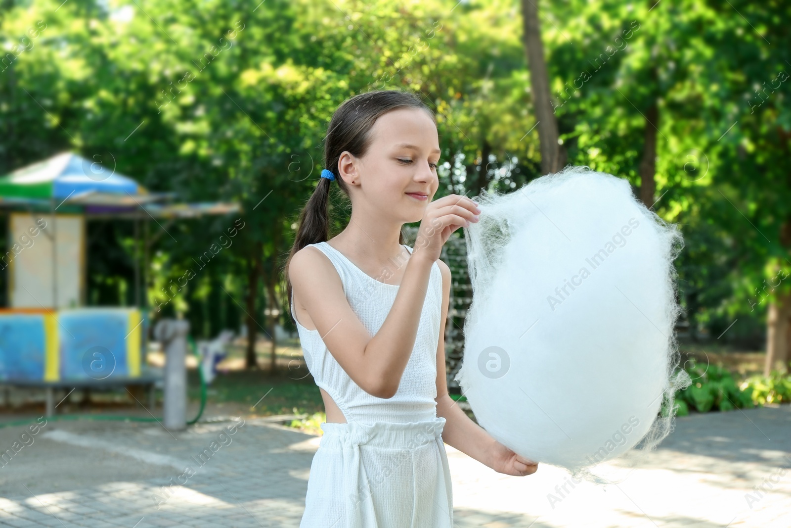 Photo of Little girl eating sweet cotton candy in park