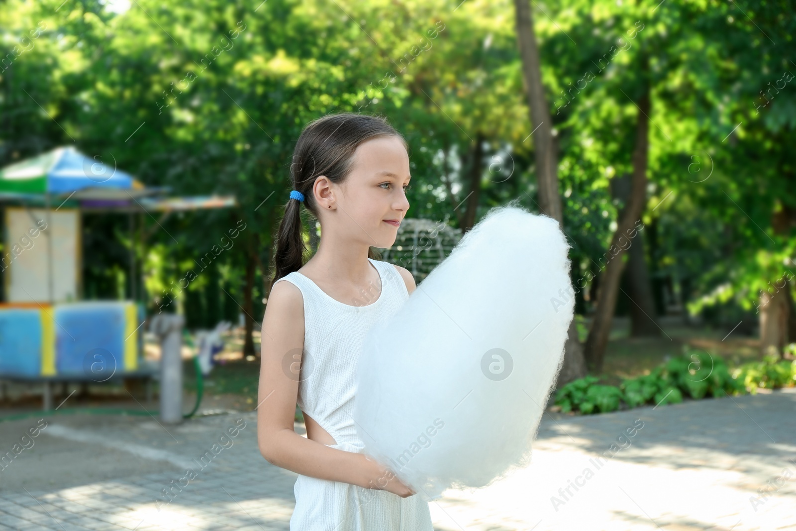 Photo of Portrait of little girl with sweet cotton candy in park