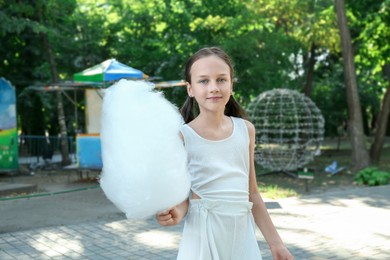 Photo of Portrait of little girl with sweet cotton candy in park